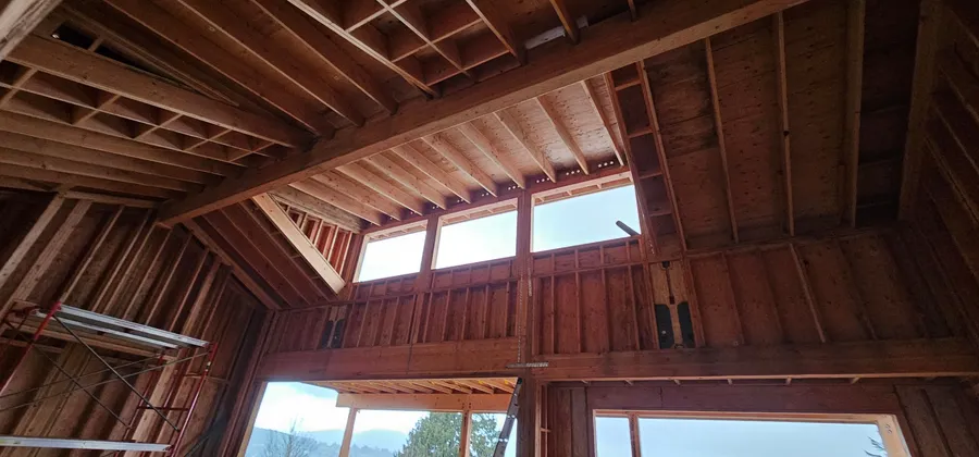 Looking up at a vaulted ceiling with timber beams, rafters, and a row of high windows