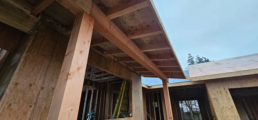 Timber post and beam framing at a covered entry, with a roof overhang and sheathed walls